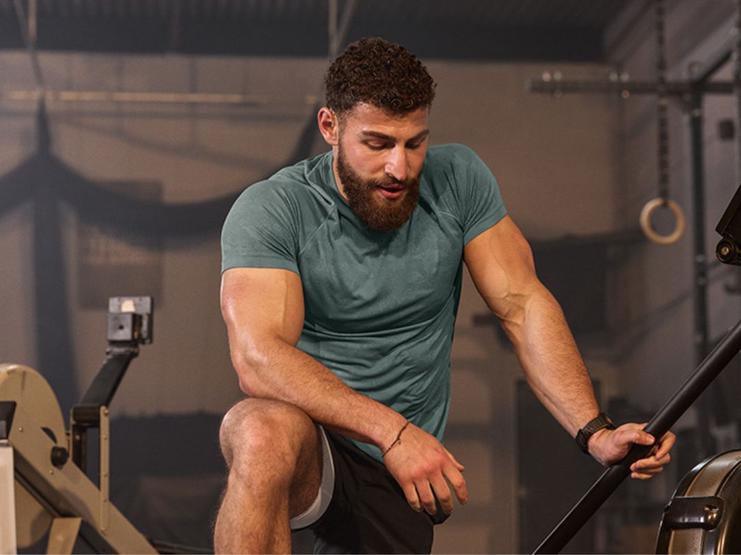 גבר אתלט נח בין סט לסט באימון הכושר שלו