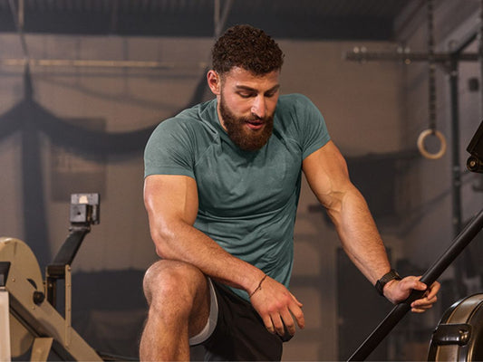 גבר אתלט נח בין סט לסט באימון הכושר שלו